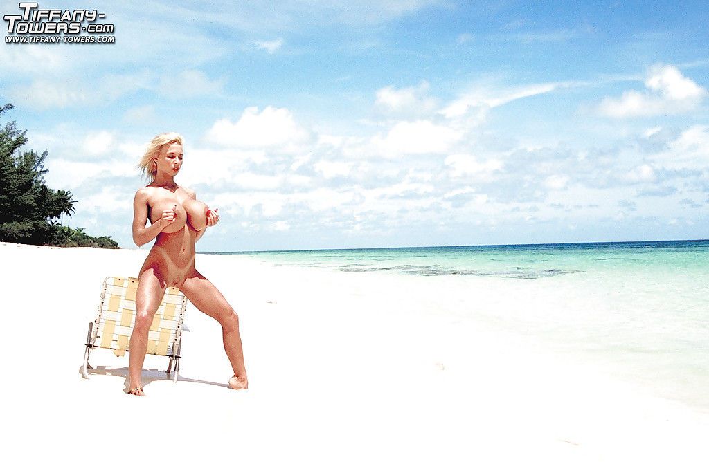 Older blonde pornstar Tiffany Towers exposing huge tits outdoors on beach