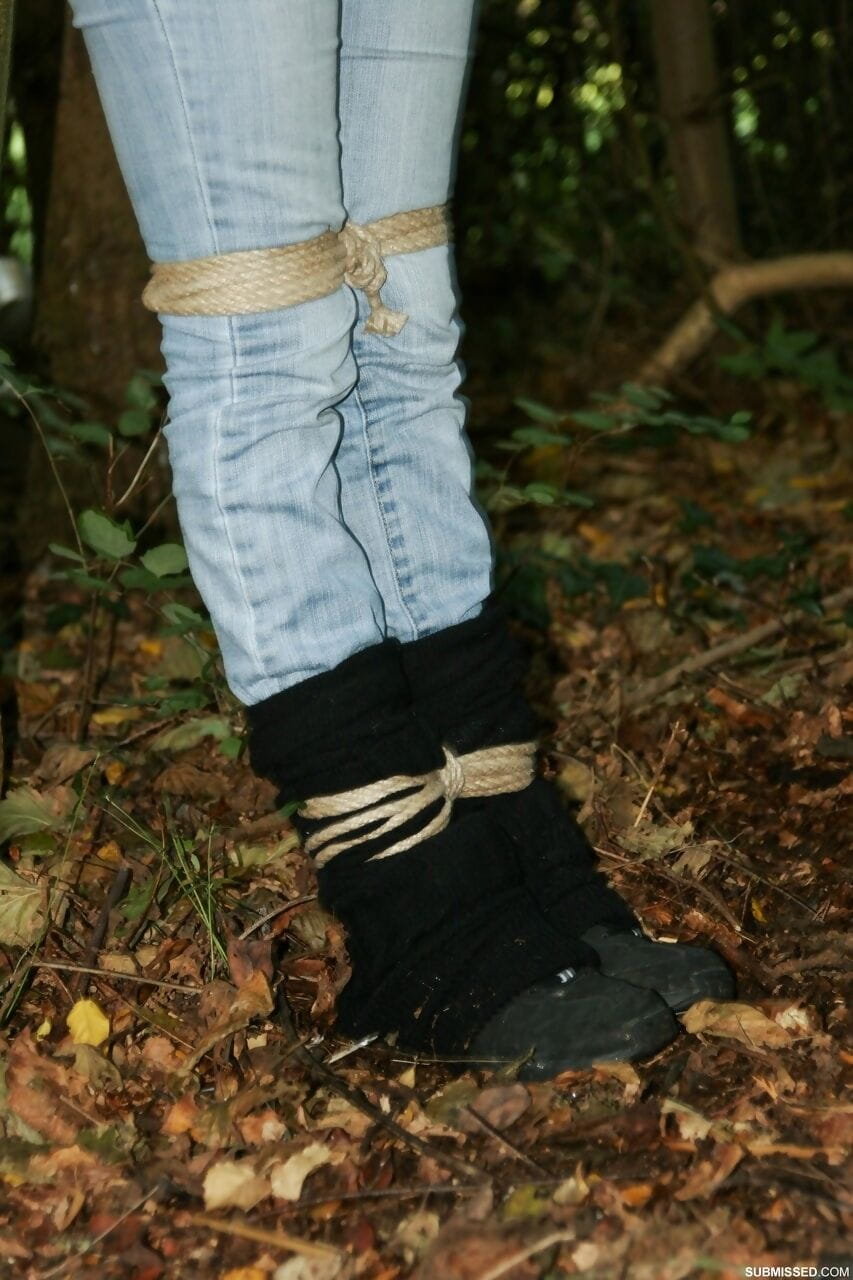 Sexy black haired Vixen gagged & roped up in jeans & boots & tied to a tree