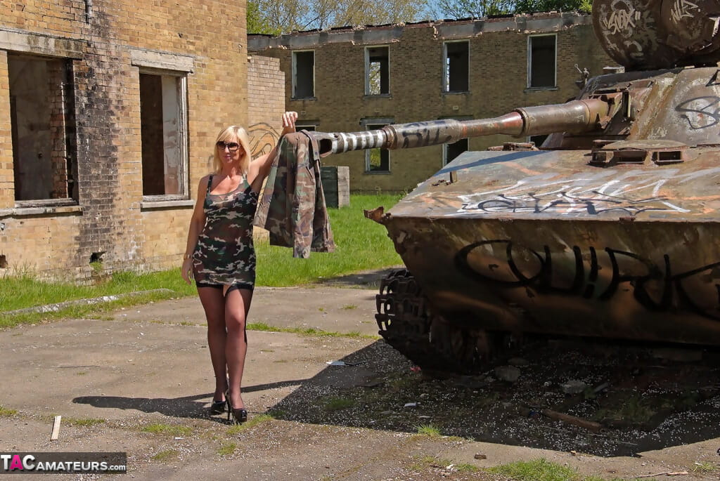 सुनहरे बालों वाली लड़की राग निकालता है उसके छलावरण पोशाक करने के लिए मॉडल , पर एक टैंक